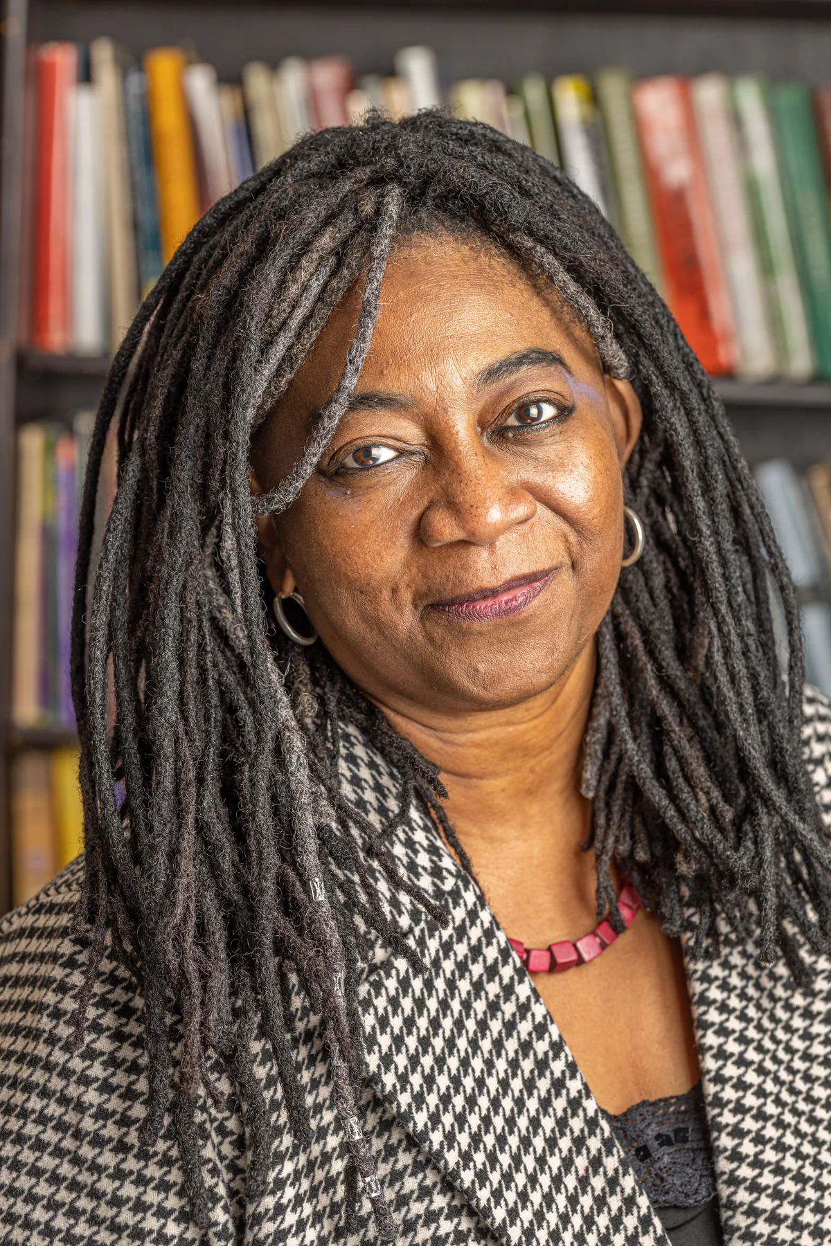 Kamari Maxine Clarke, portrait photographed in front of a bookshelf